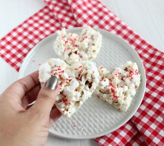 white chocolate popcorn in heart shapes with red checkers kitchen towel