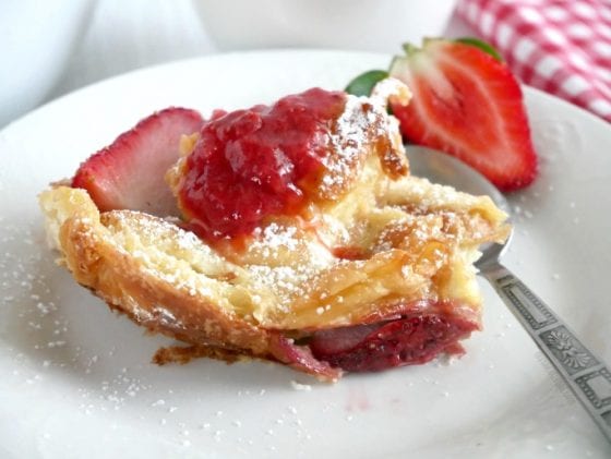 A serving of Strawberry and Cream Croissant Bread Pudding topped with a spoonful of homemade Strawberry Compote with a side of fresh strawberries. Grab the recipe at mysweetzepol.com #brunch #breadpudding #freshstrawberries
