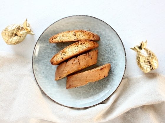 Biscotti in a beautiful blue dish with gold pineapples beside the dish! Piña Colada Biscotti is the best way to bring those tropical flavors you love so much. Bring tha warm weahter we've been craving for into your kitchen. Grab the recipe @ mysweetzepol.com #EasterSweetsWeek #ad