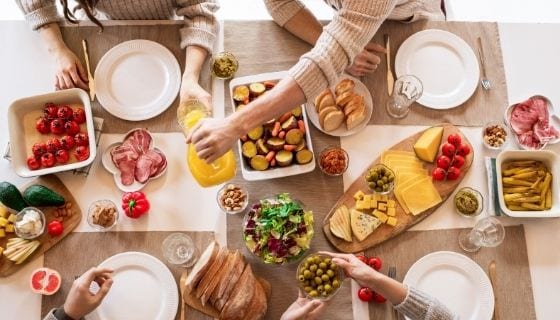 gathered by the table filled with food to enjoy during Christmas day dinner