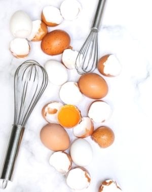 whisks in a marble counter slab with eggs and eggshells