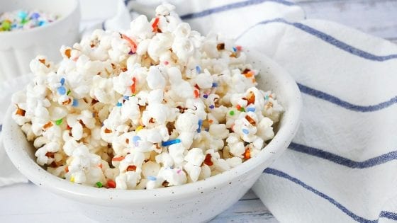 homemade popcorn with white chocolate and rainbow colors sprinkles with kitchen towel