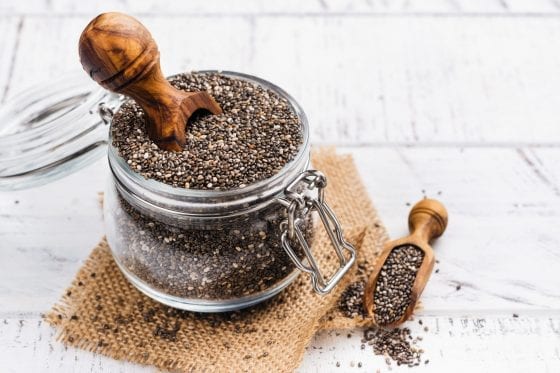 Chia seeds on kitchen counter with wood kitchen utensils and cream color rag